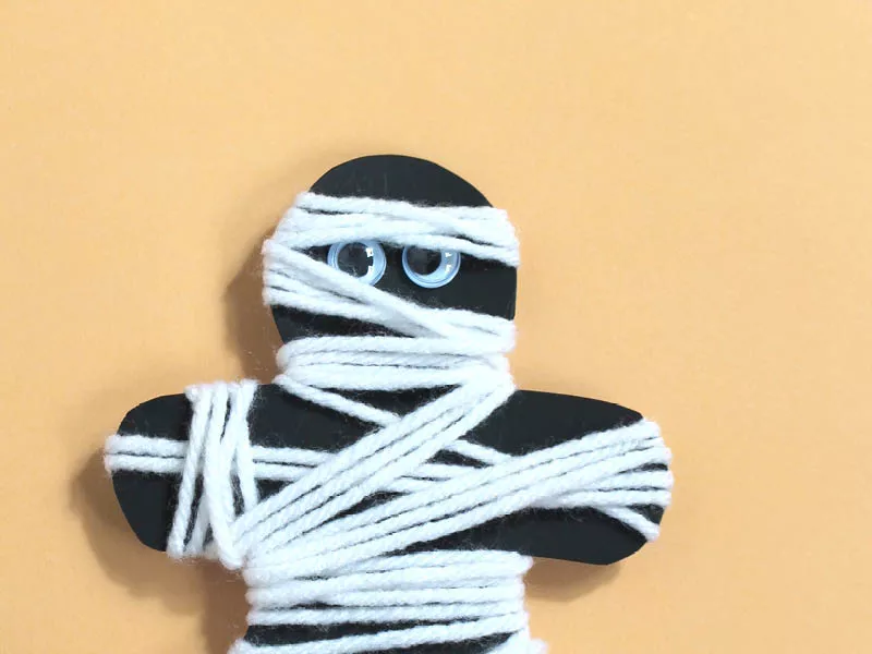 Paper person cutout mummified in white yarn