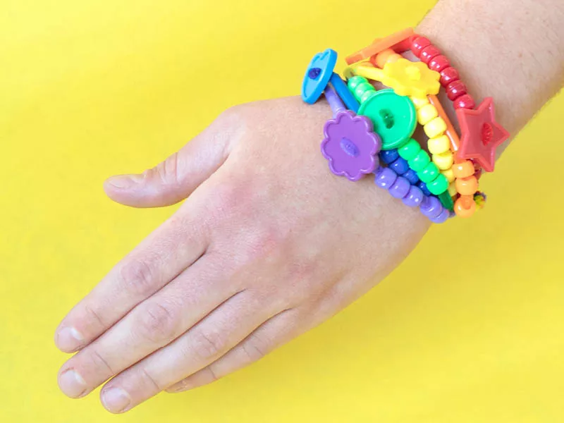 Hand with a rainbow of colored plastic bracelets around the wrist